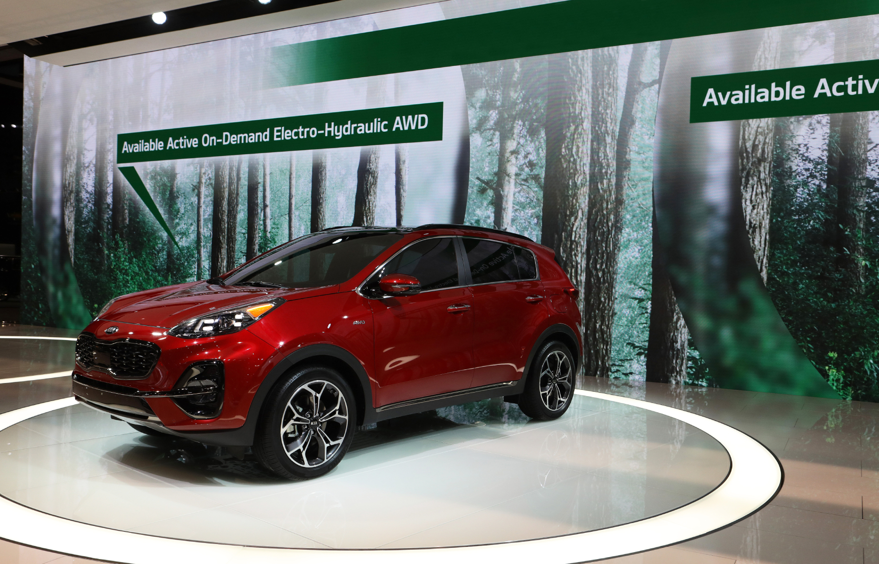 A Kia Sportage on display at an auto show advertising its available all-wheel-drive system