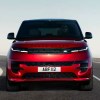 A red Land Rover Range Rover Sport is driving on the road.
