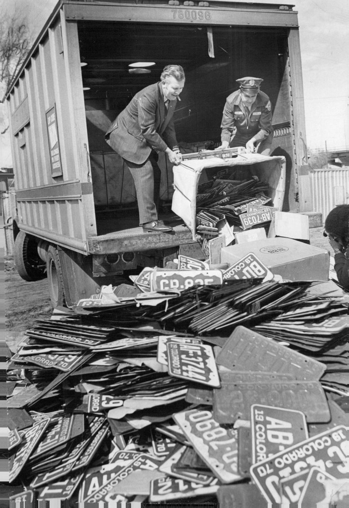 2 Postal Service workers dispose of old license plates in Denver in 1971