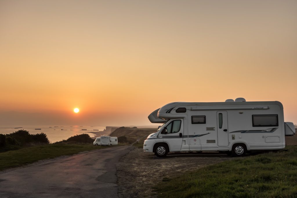 two motorhomes parked on small road beside coast of the sea
