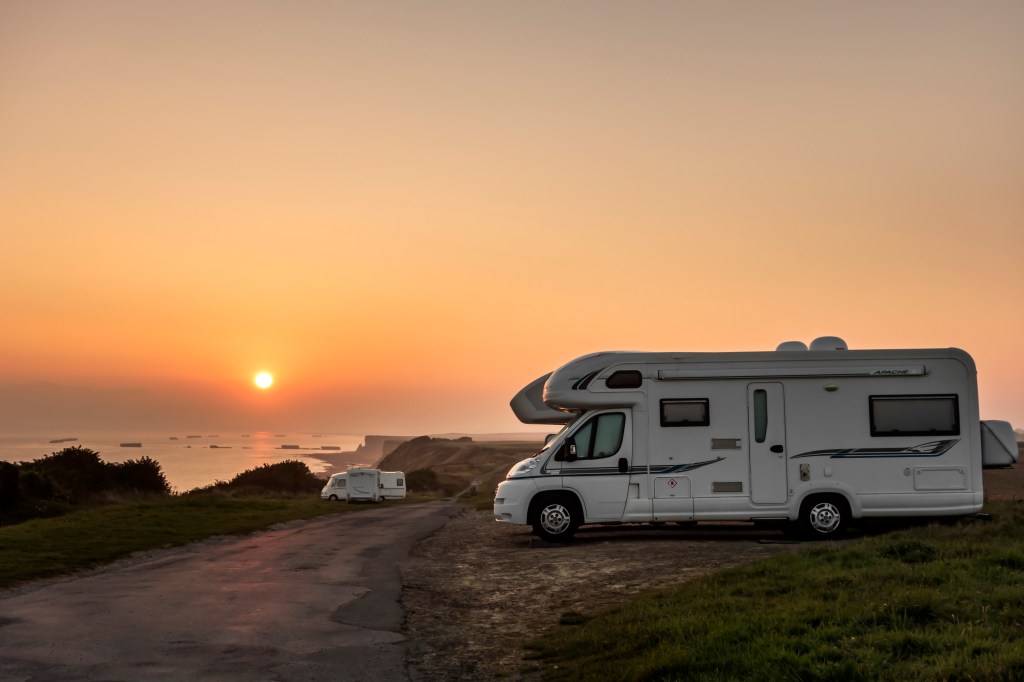 Motorhomes parked along the coast at sunset with view over the sea