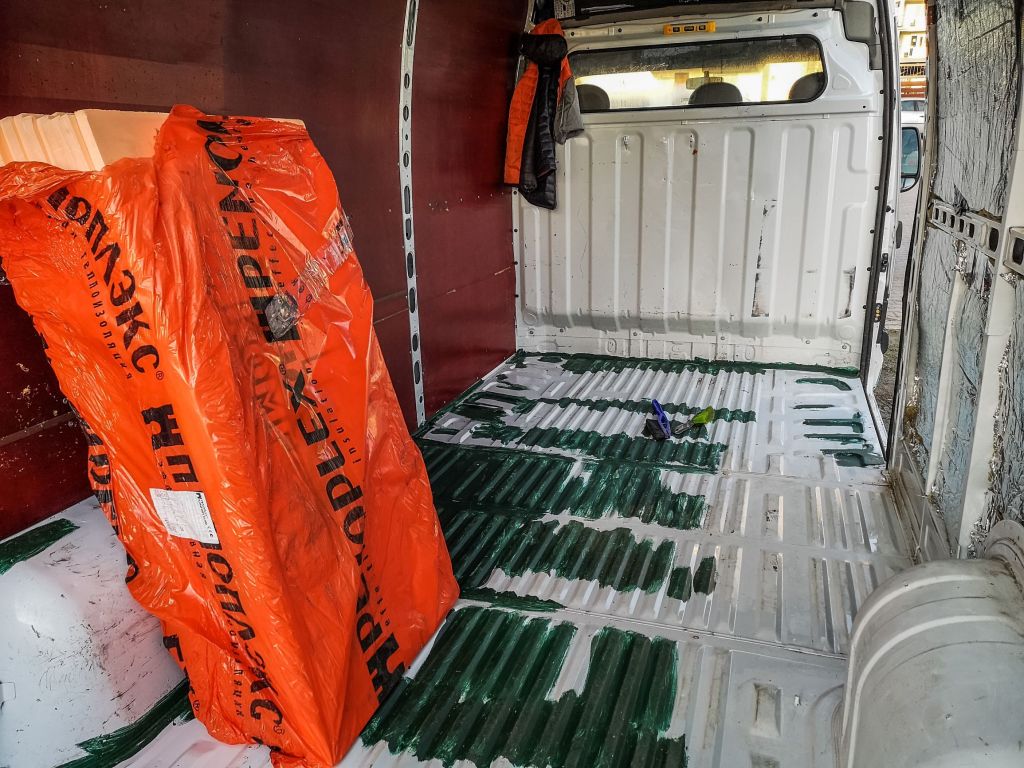 Orange Penoplex polystyrene insulation boards in a stripped-down camper van