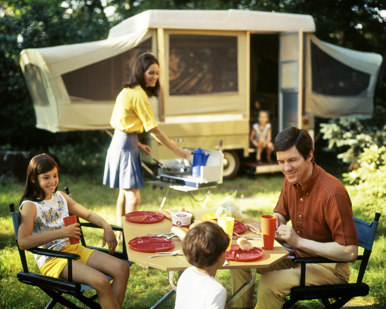 A family smiles outside of their pop-up camper