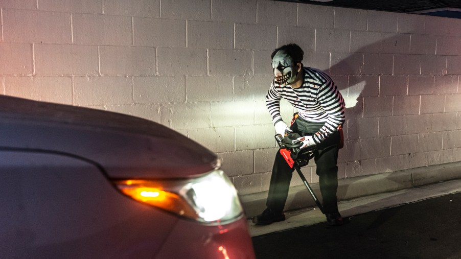 A person in Halloween costume in front of a car