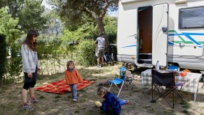 A family at a camp site with an RV in the background