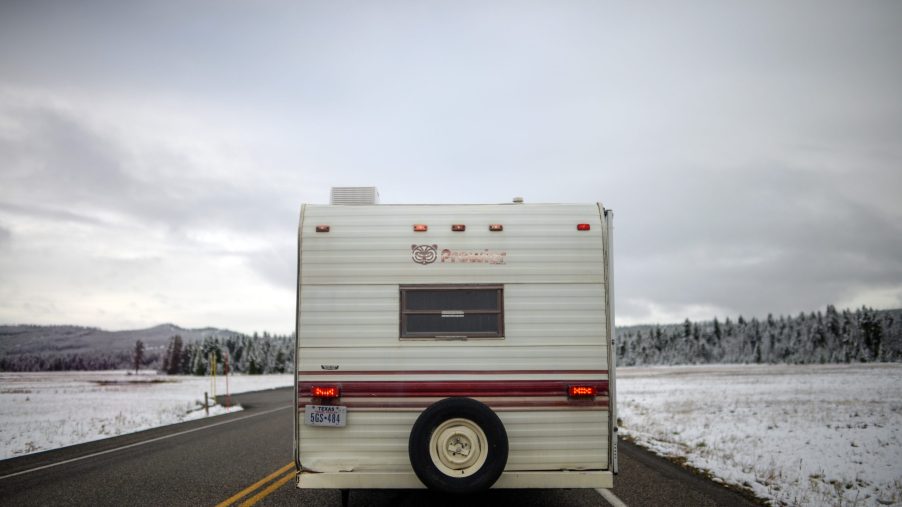 RV camper drives on road with winter landscape