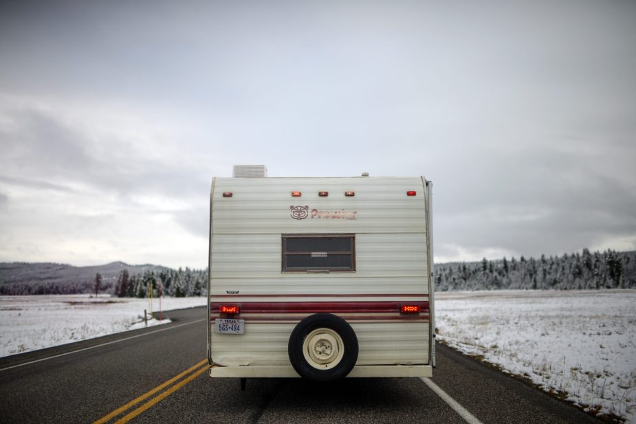 RV camper drives on road with winter landscape