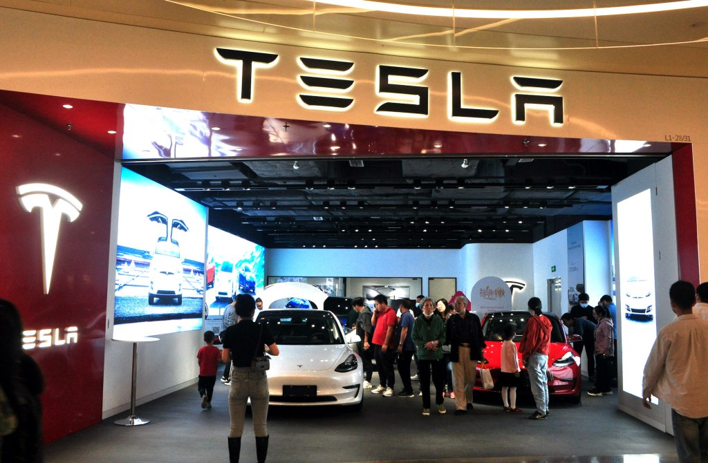 People look at electric vehicles at a Tesla store