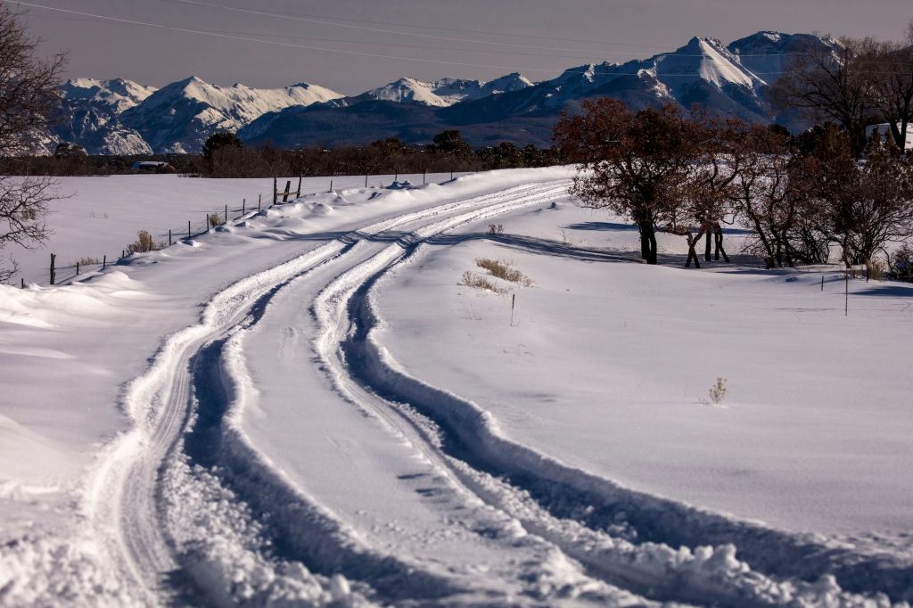 Winter snowy road through deep snow leads to San Juan Mountains. Overlanding at its best.