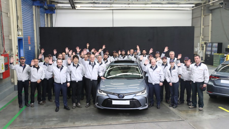 Toyota factory workers posing next to a new car
