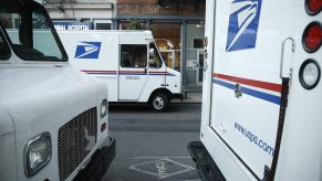 Three USPS trucks are awaiting loading and unloading.