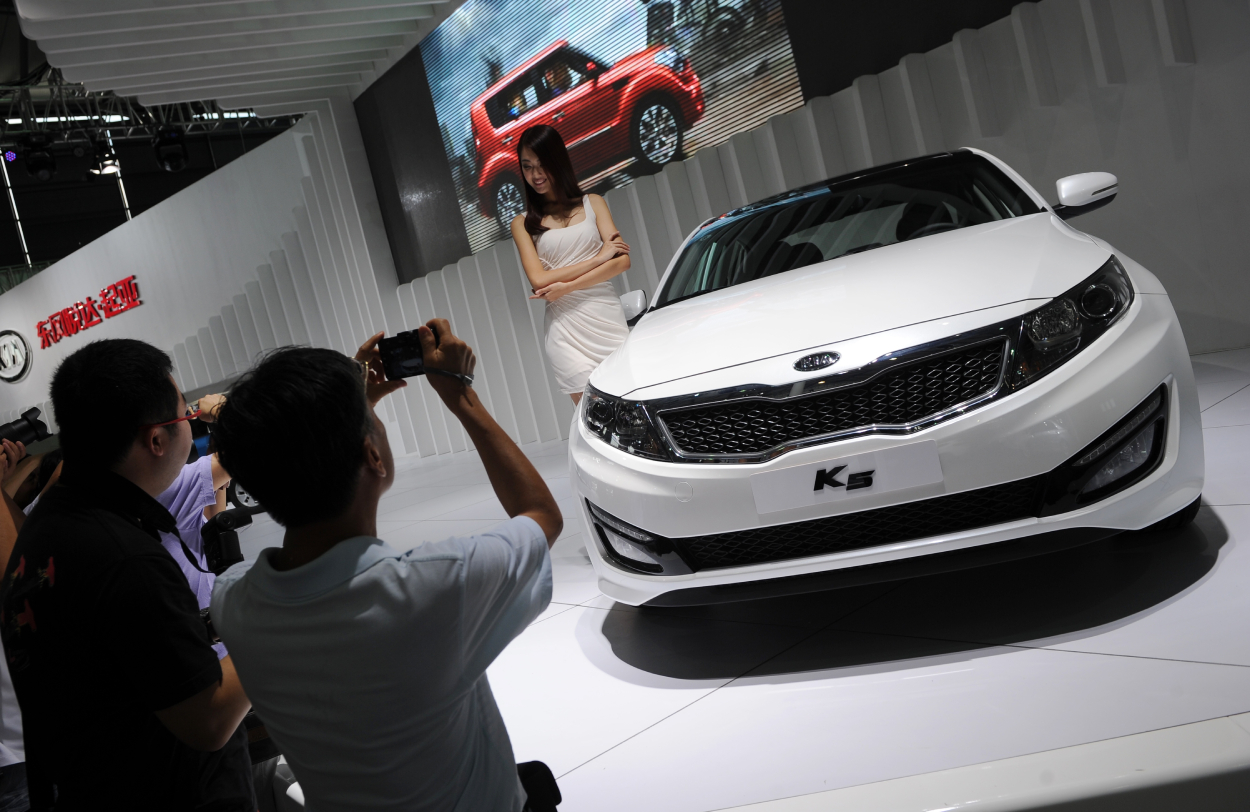 A person takes a picture of a Kia K5 on display