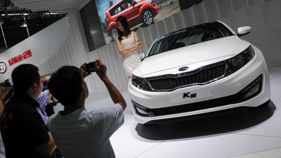 A person takes a picture of a Kia K5 on display