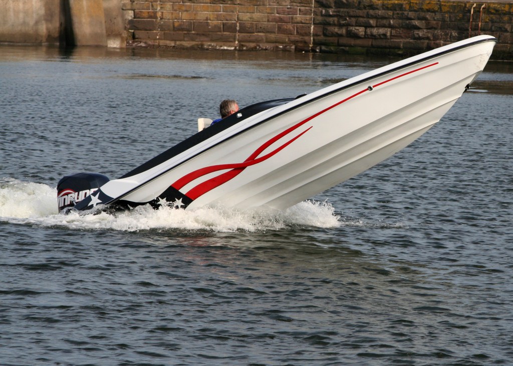 speed boat with its nose out of the water, exposing the bottom of the boat above the water