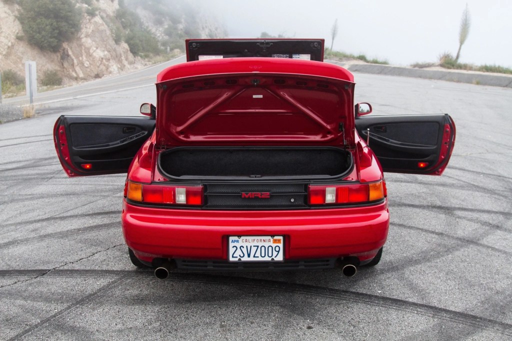 The rear view of a red 1991 Toyota MR2 Turbo with its doors, engine cover, and rear trunk open