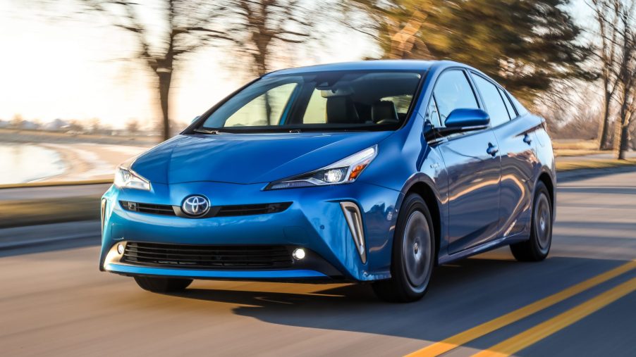 blue Toyota Prius at speed on a lakeside road