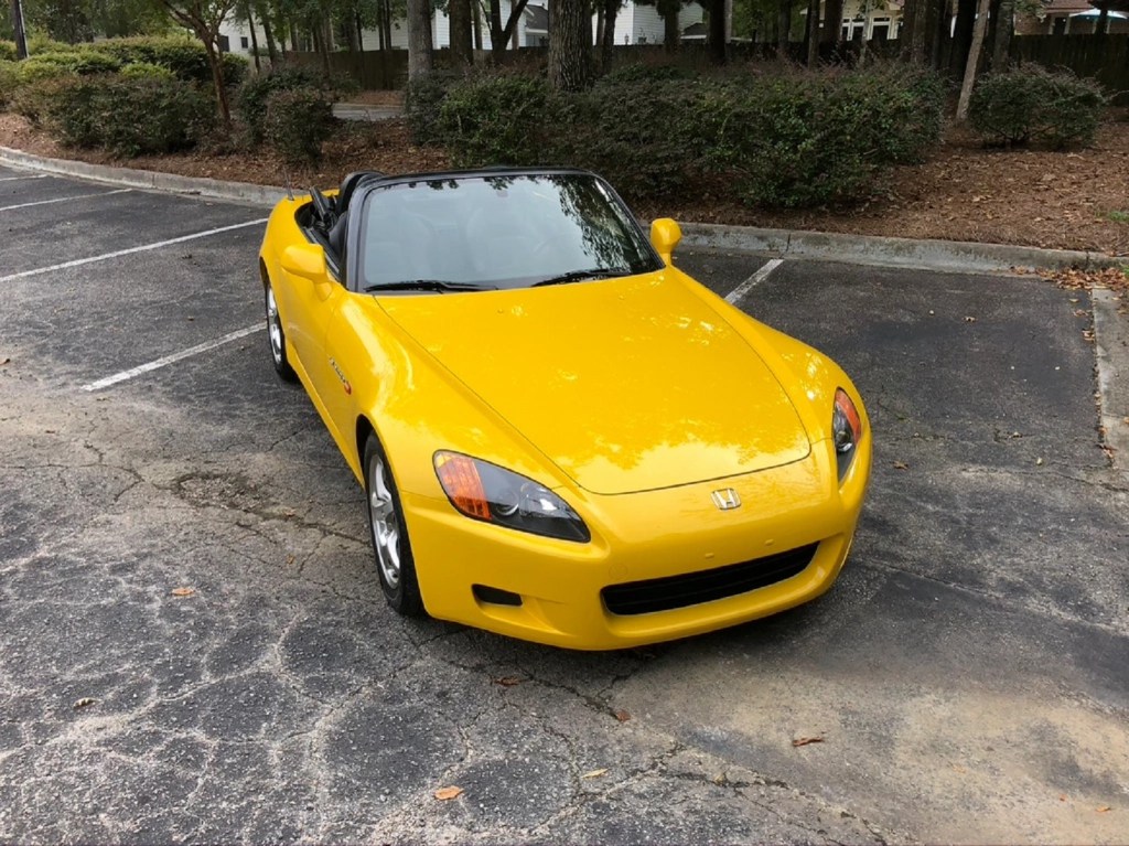 A yellow 2002 Honda S2000 in a parking lot