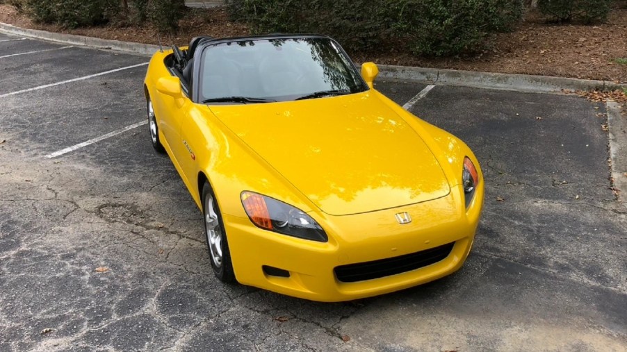 A yellow 2002 Honda S2000 in a parking lot