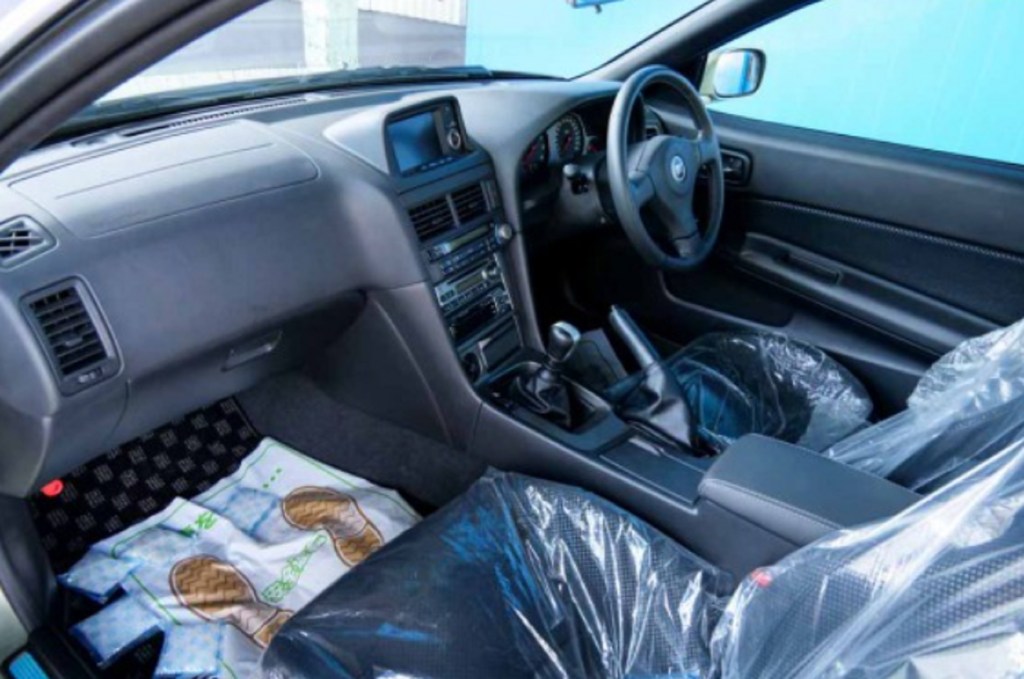 The plastic-wrapped front seats and black dashboard of a 2002 R34 Nissan Skyline GT-R V-Spec II Nur