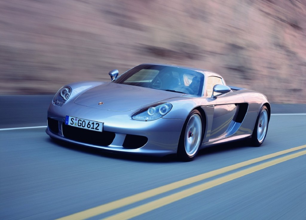 A silver 2004 Porsche Carrera GT drives through a canyon