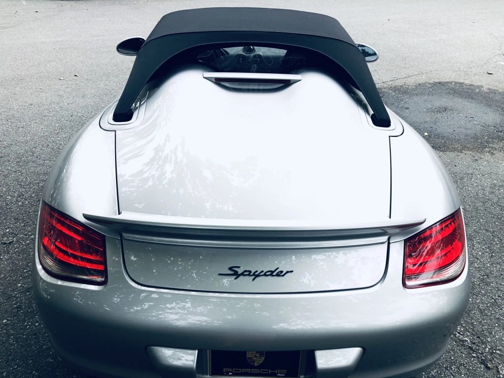 The rear view of a silver 2011 Porsche Boxster Spyder with its top up