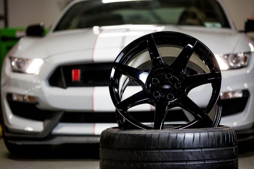 A gray-and-white 2016 Ford Shelby GT350R Mustang behind its black carbon-fiber wheel