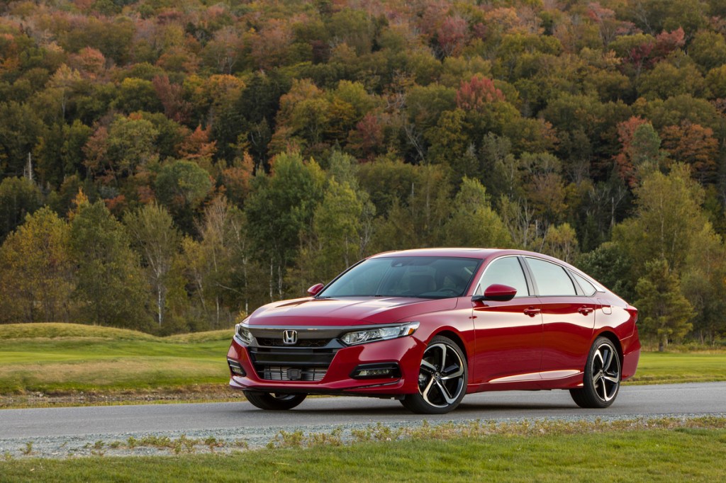 the 2020 Honda Accord in red on a scenic road with a forested landscape in the background