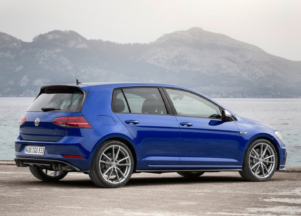 The rear 3/4 view of a blue 2019 Volkswagen Golf R by a lake