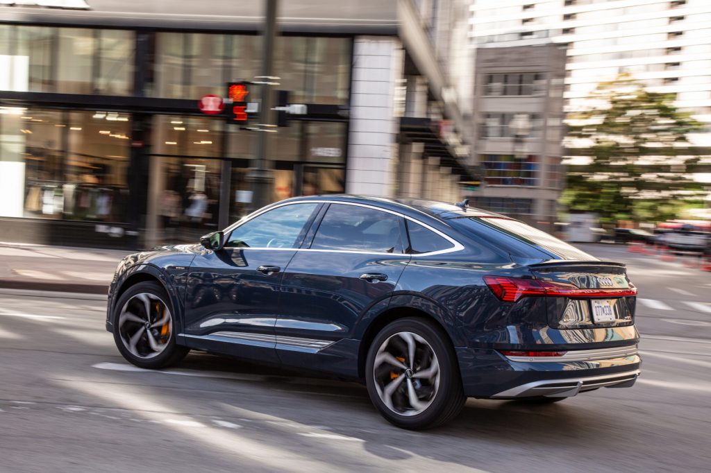 A blue 2020 Audi e-tron driving down a city street