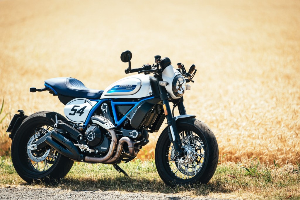 A silver-and-blue 2020 Ducati Scrambler Cafe Racer by a field