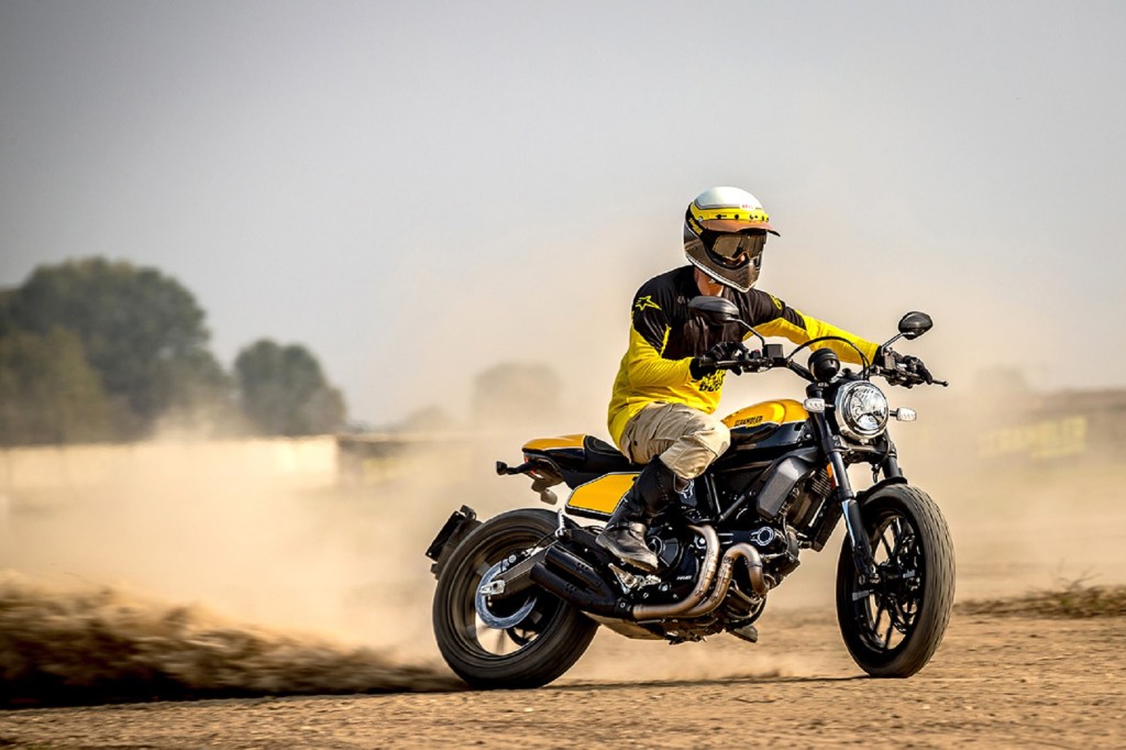 A rider drifts a black-and-yellow 2020 Ducati Scrambler Full Throttle in the desert