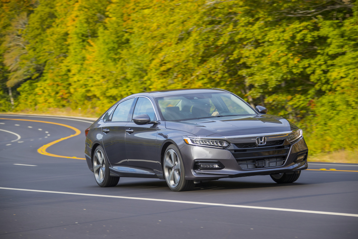 a gray 2020 Honda Accord touring at speed on a scenic road surrounded by forest