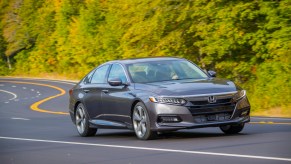 a gray 2020 Honda Accord touring at speed on a scenic road surrounded by forest