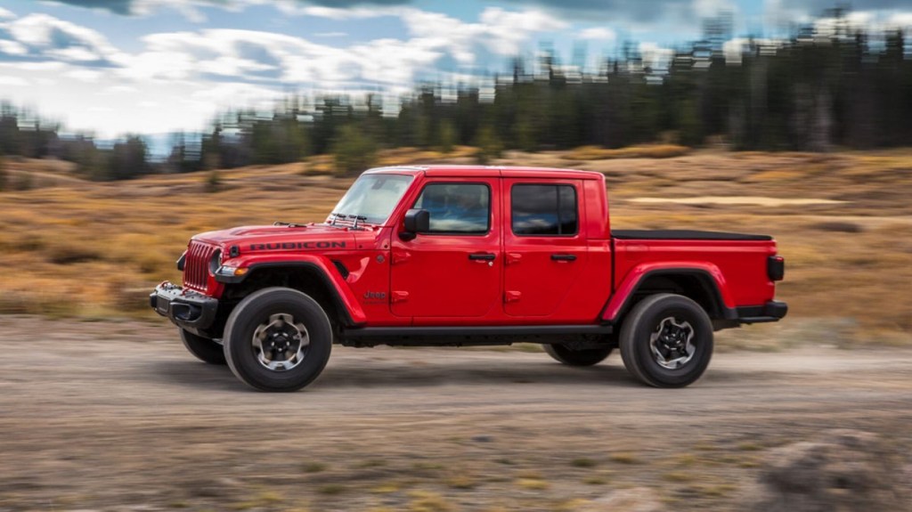 A red 2020 Jeep Gladiator Rubicon drives on a mountain plain trail