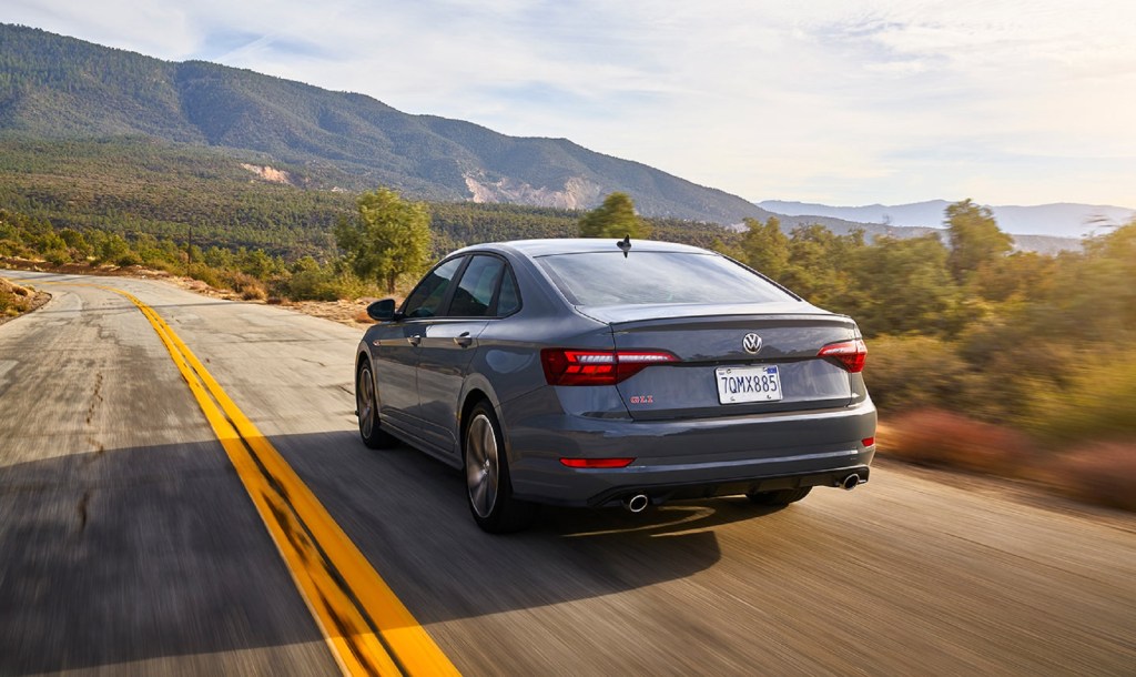 The rear 3/4 view of a gray 2020 Volkswagen Jetta GLI Autobahn driving on a desert plains road