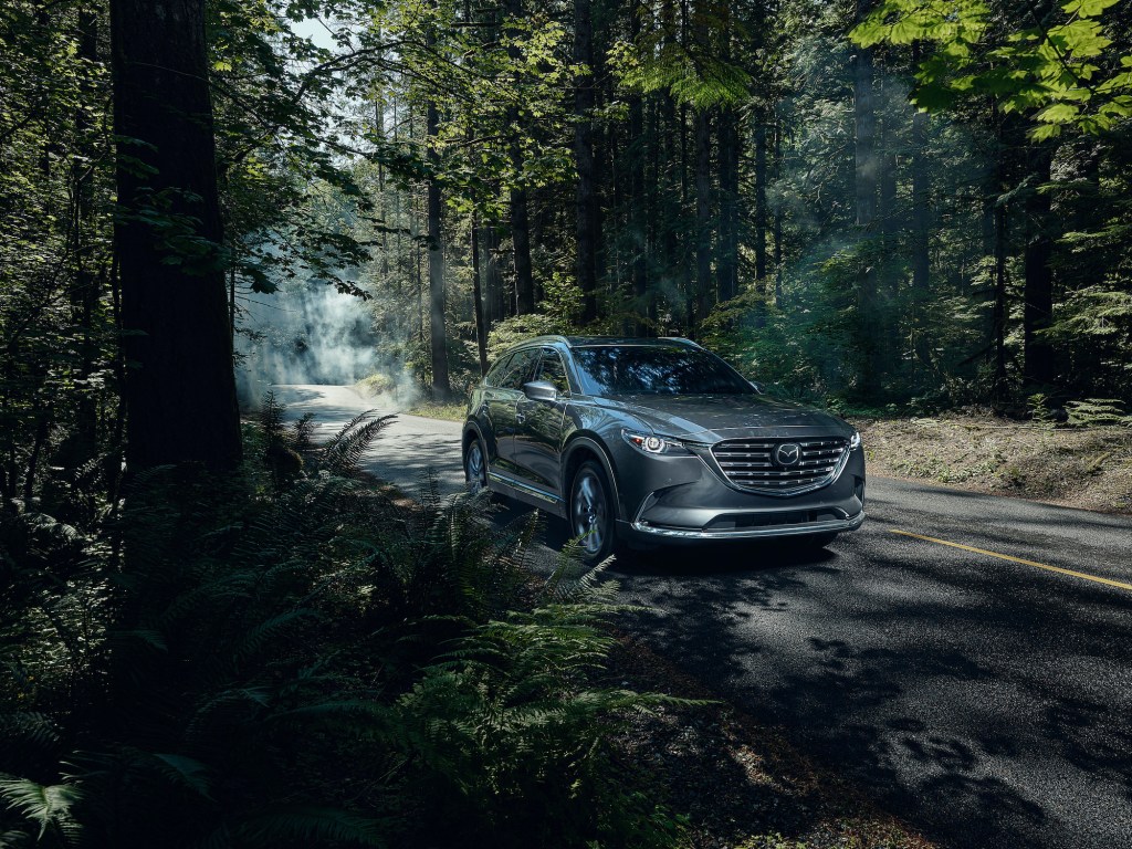 a silver 2021 Mazda CX-9 driving down a remote forest road. 