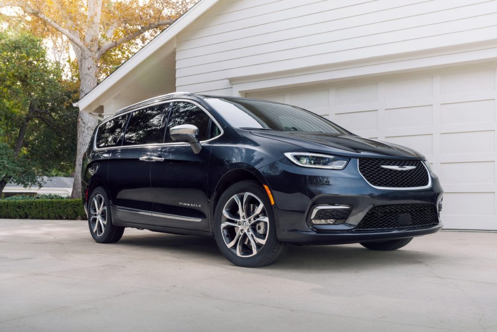 A blue 2021 Chrysler Pacifica parked in a driveway in front of a garage