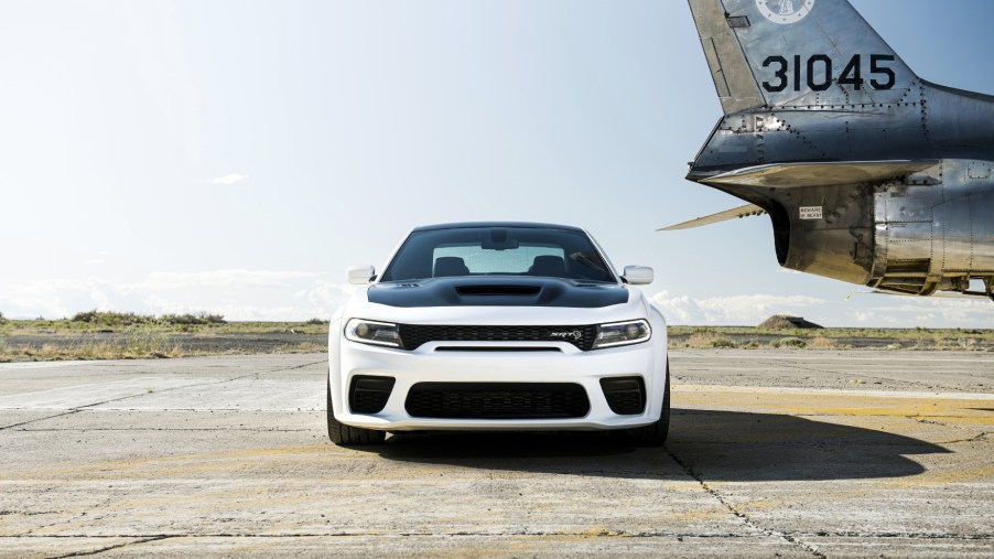 A white and black 2021 Dodge Charger Hellcat Redeye on display next to an airplane