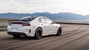 The rear 3/4 view of a white 2021 Dodge Charger SRT Hellcat Redeye on a racetrack