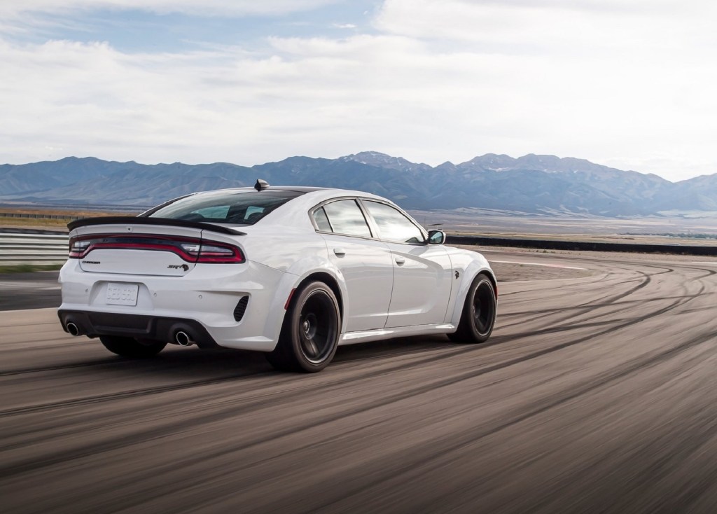 The rear 3/4 view of a white 2021 Dodge Charger SRT Hellcat Redeye on a racetrack