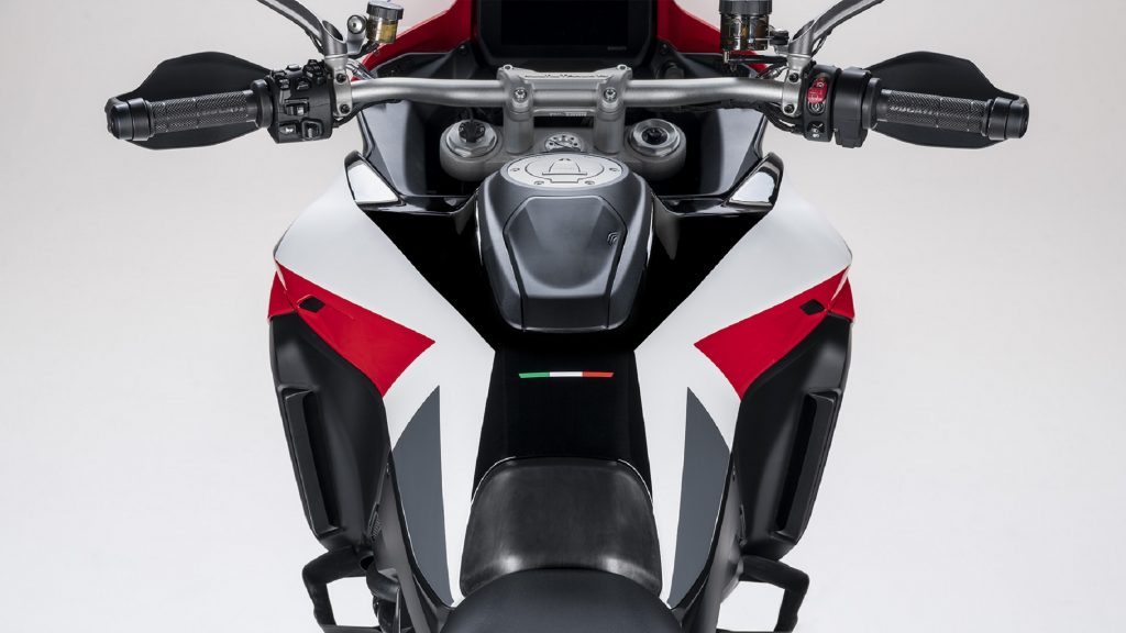 The handlebars, fuel tank, and dash of a red-and-white 2021 Ducati Multistrada V4 S