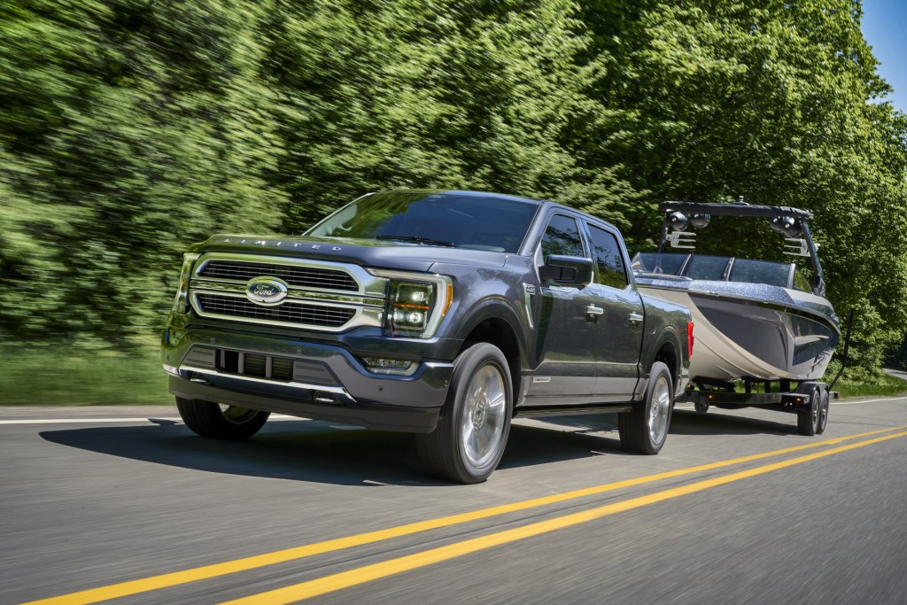 A grey 2021 Ford F-150 towing a boat on highway | new car sales
