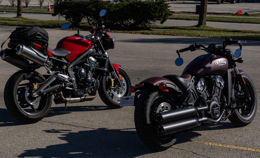The rear 3/4 view of a red 2012 Triumph Street Triple R next to a maroon 2021 Indian Scout Bobber