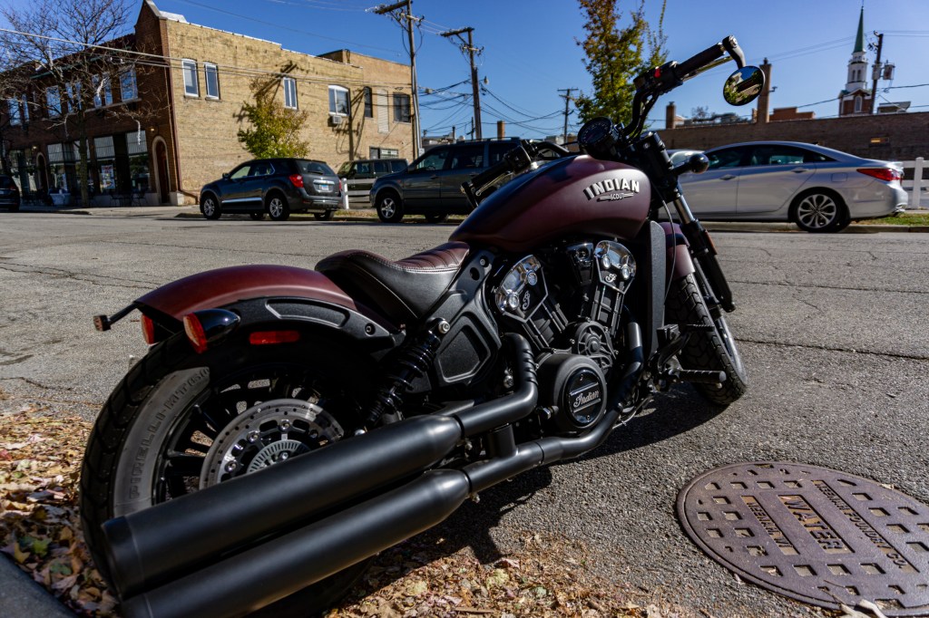 The rear 3/4 view of a maroon 2021 Indian Scout Bobber parked on the street