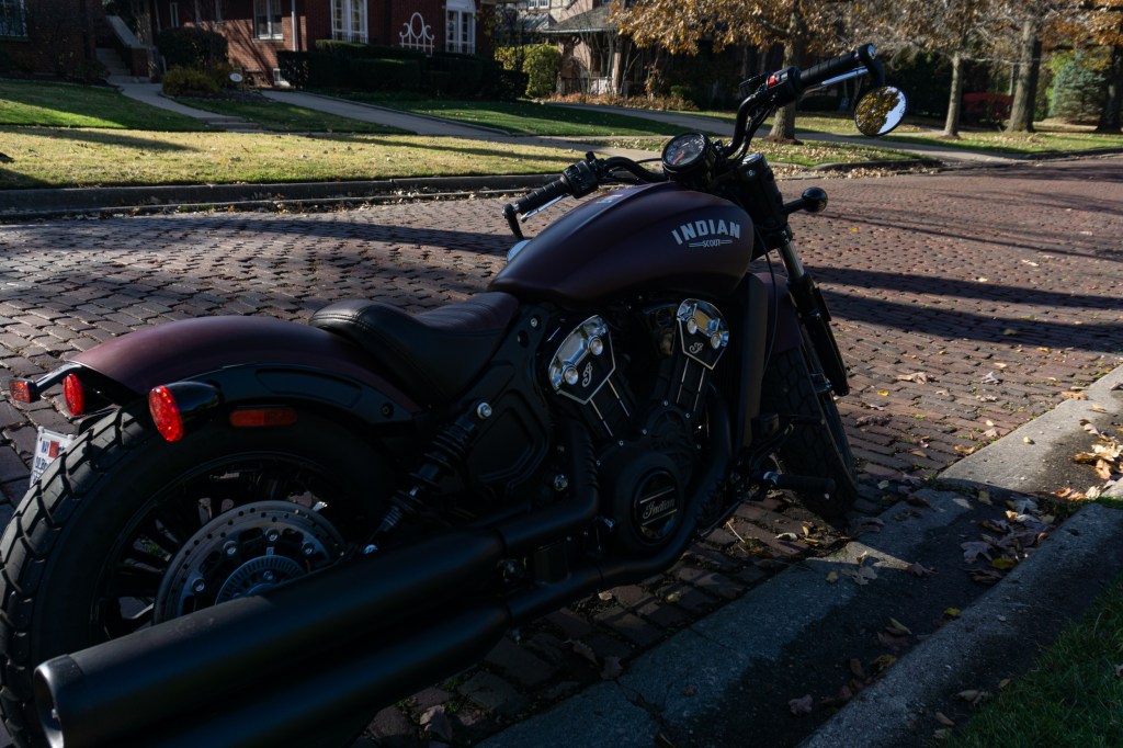 The rear 3/4 view of a maroon 2021 Indian Scout Bobber on a cobblestone street