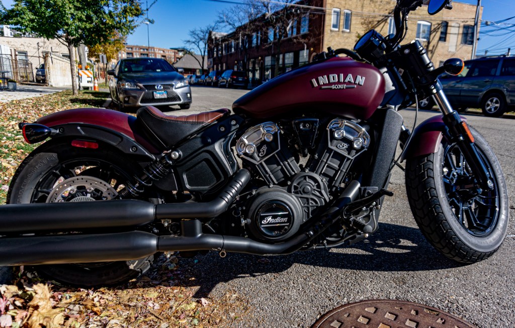 The side view of a maroon 2021 Indian Scout Bobber parked on the street