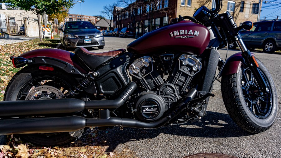 The side view of a maroon 2021 Indian Scout Bobber parked on the street