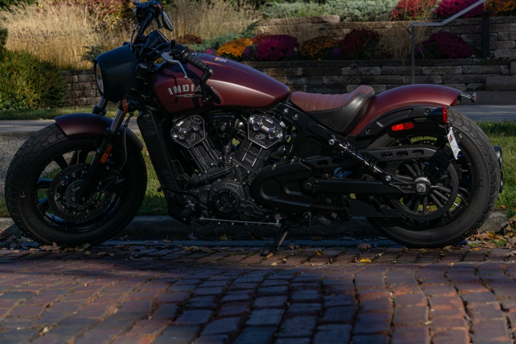 The side view of a maroon 2021 Indian Scout Bobber on a cobblestone street