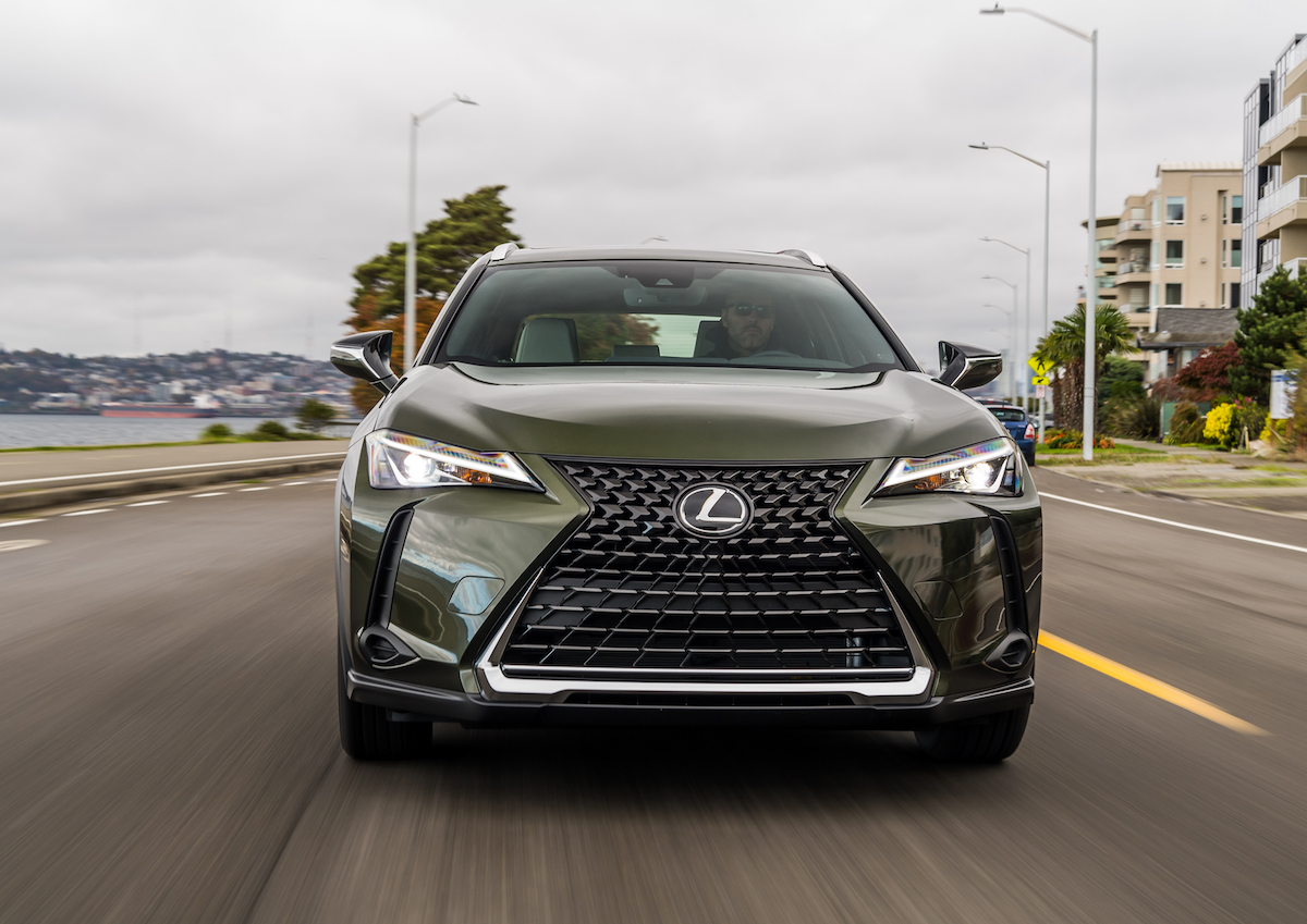 The front of a green 2021 Lexus UX on the road. Many drivers opt to buy a new Lexus because of its luxurious interior.