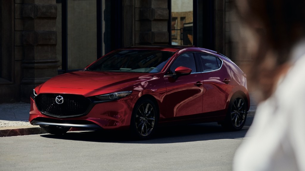 The front 3/4 view of a red 2021 Mazda3 Turbo Premium Plus on a city street